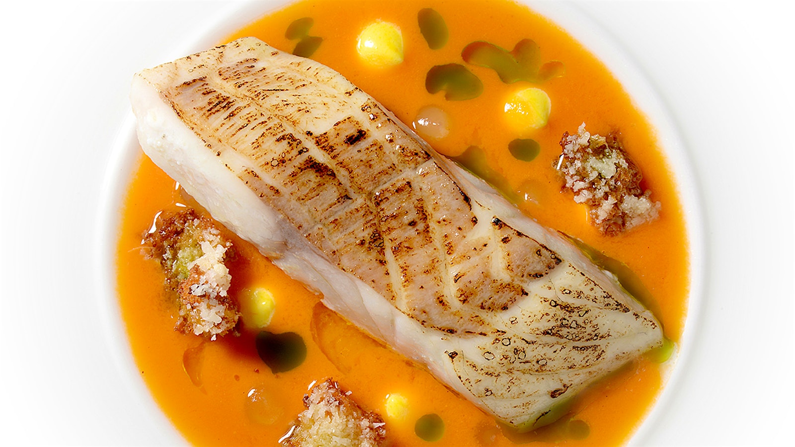 A plate of white haddock fish in an orange sauce at Northcote